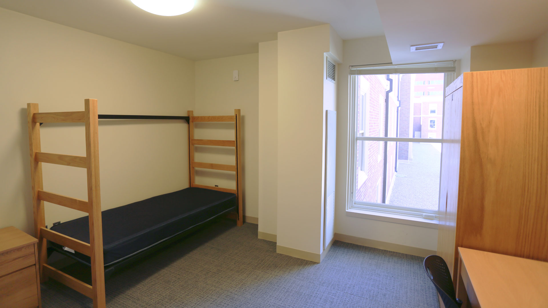 View of a resident room with a bed, desk, and wardrobe