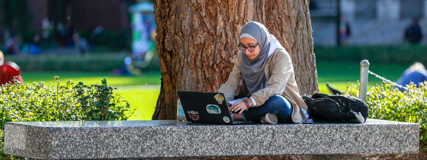 Student sitting outside with a laptop