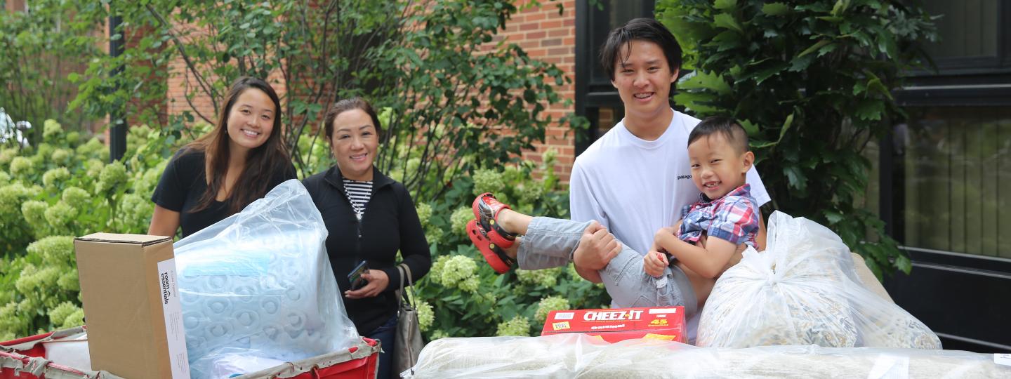 Parent, student, and younger siblings on move in day with carts of supplies