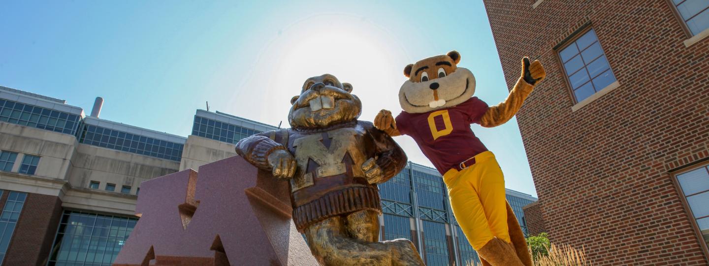 Goldy mascot posing next to Goldy statue