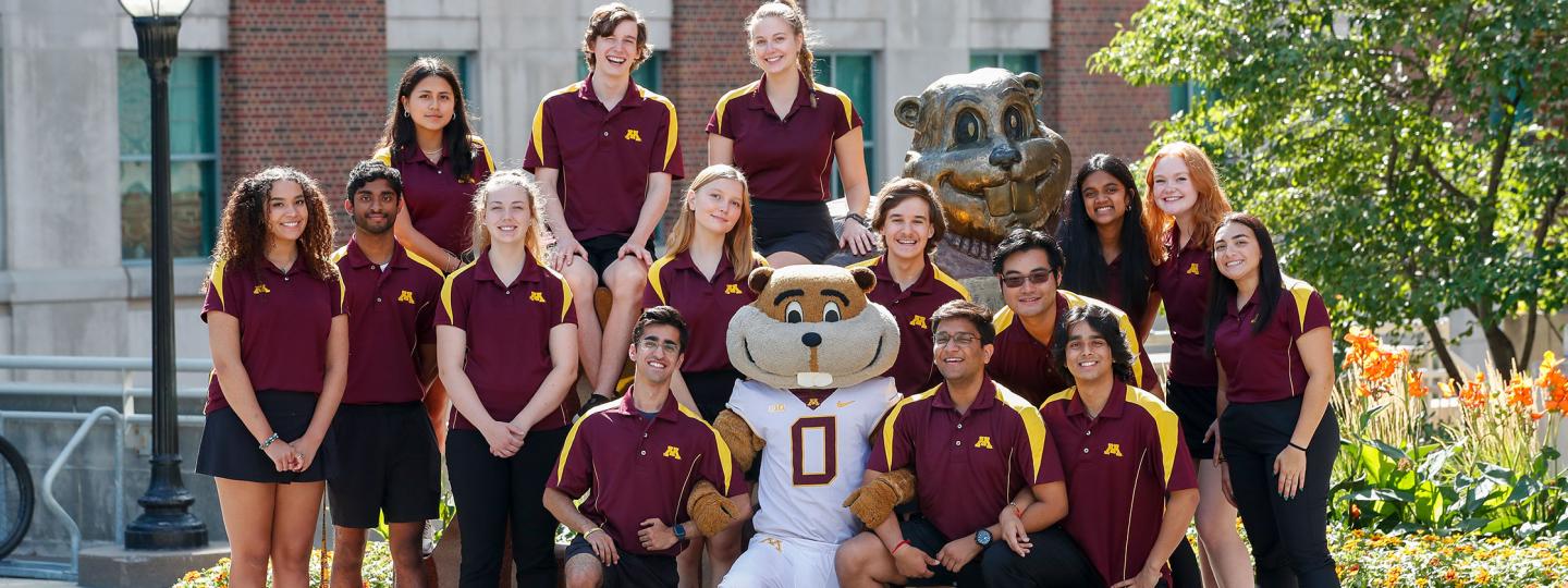 students posing with goldy in front of the goldy statue