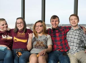 Five students sit together in a lounge at 17th Ave Residence Hall
