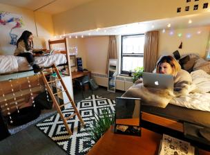 Two roommates in Sanford Hall studying on their beds with laptops