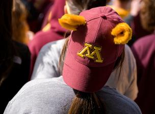 A person wearing a backward U of M hat with gopher ears on top