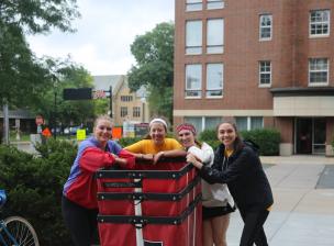 Four students standing outside with moving carts