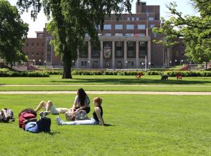 Students on the grass in the mall area with coffman in the background