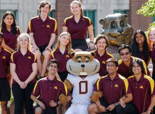 students posing with goldy in front of the goldy statue