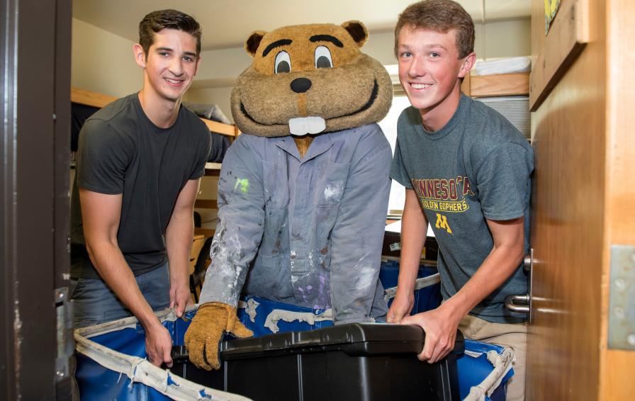 Goldy mascot posing with two roommates during move-in
