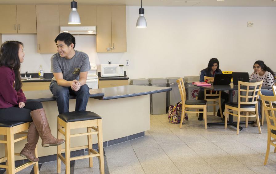Students hanging out in the kitchenette area of the club room.